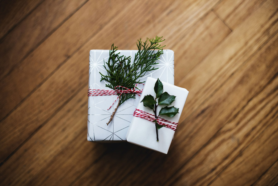 White wrapped presents tied with red ribbon and foliage