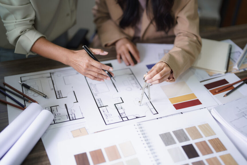 Two female architects discuss interior design building project and use divider compass on blueprint stock photo